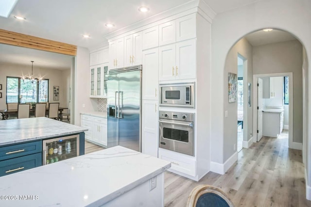 3605 N Langdale Trl, Flagstaff, AZ 86001 - kitchen featuring appliances with stainless steel finishes, wine cooler, arched walkways, white cabinetry, and recessed lighting