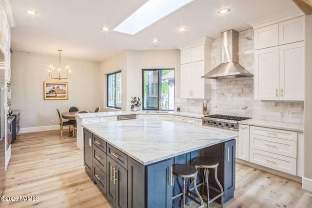 3605 N Langdale Trl, Flagstaff, AZ 86001 - kitchen featuring wall chimney exhaust hood, white cabinets, light wood finished floors, backsplash, and a chandelier