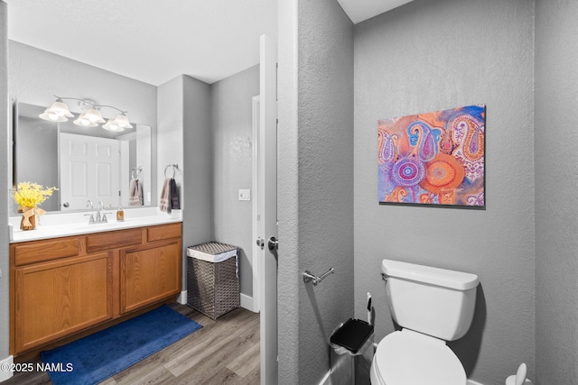 bathroom featuring toilet, wood finished floors, vanity, and baseboards