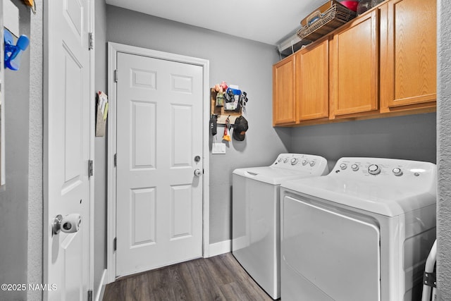 clothes washing area featuring cabinet space, washer and clothes dryer, baseboards, and dark wood-style flooring