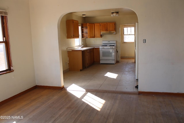 kitchen featuring white range with gas cooktop, sink, and light wood-type flooring