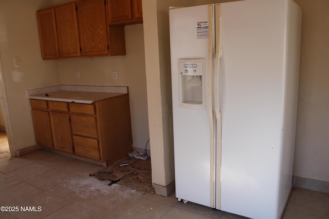 kitchen featuring white fridge with ice dispenser and light tile patterned flooring