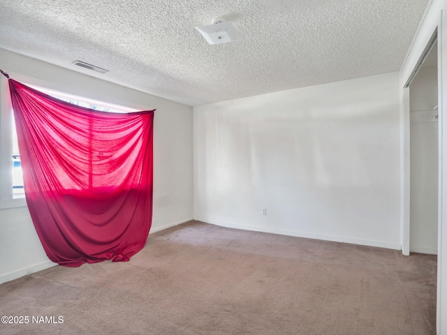 carpeted empty room featuring a textured ceiling