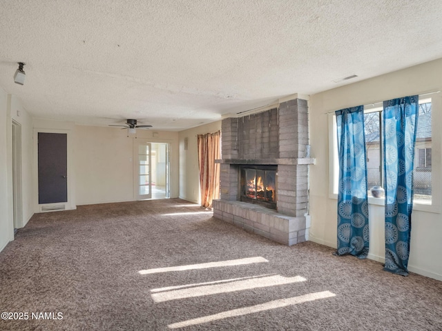 unfurnished living room with ceiling fan, carpet, a textured ceiling, and a fireplace