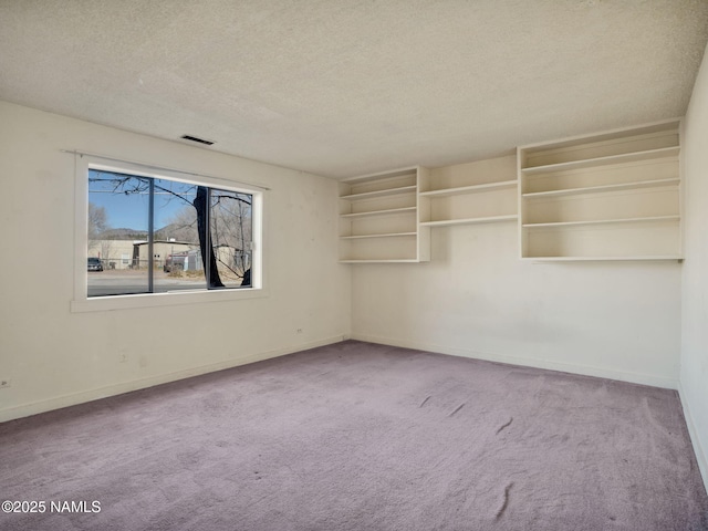 carpeted empty room featuring a textured ceiling