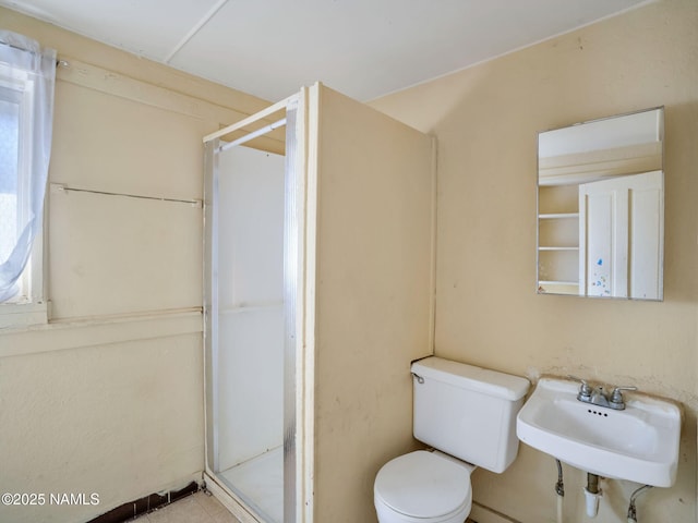 bathroom with a shower with door, sink, and toilet