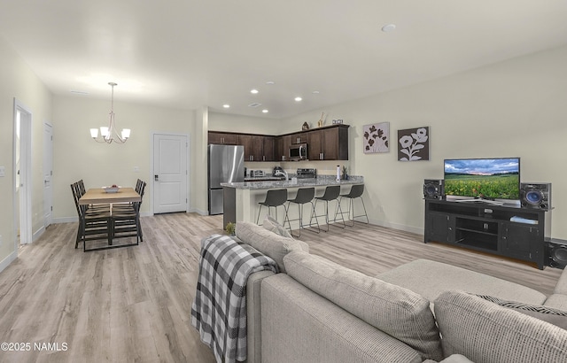 living room with recessed lighting, light wood-style flooring, a chandelier, and baseboards
