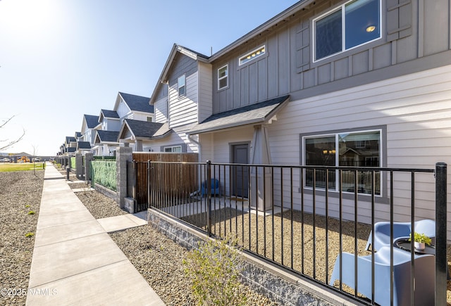 exterior space featuring board and batten siding, a residential view, and fence private yard