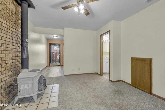 501 W Santa Fe Ave Unit 28, Flagstaff, AZ 86001 - unfurnished living room featuring a wood stove, a ceiling fan, light colored carpet, brick wall, and baseboards