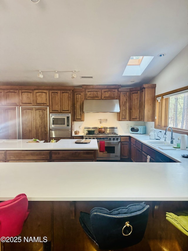 5070 N Weatherford Rd, Flagstaff, AZ 86001 - kitchen featuring a skylight, light countertops, stainless steel appliances, range hood, and a warming drawer