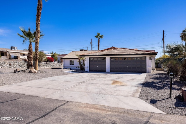 single story home with a garage, a tile roof, driveway, and stucco siding