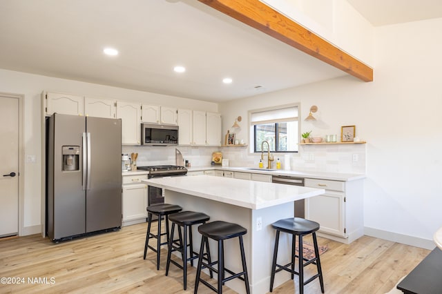 kitchen featuring white cabinets, a kitchen bar, and appliances with stainless steel finishes