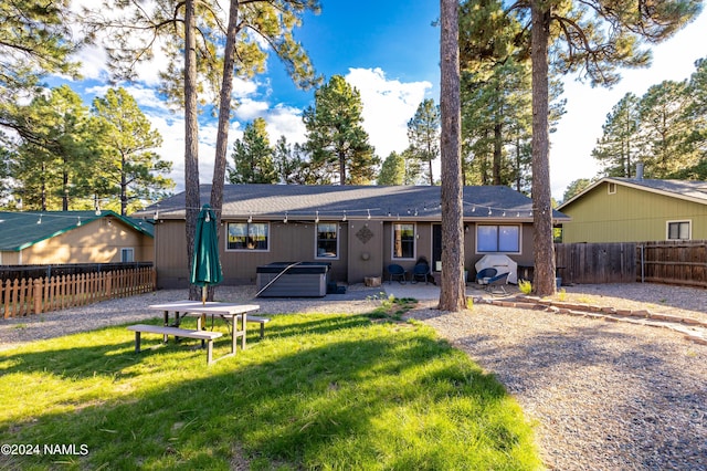 back of property featuring a patio area, a yard, and a hot tub