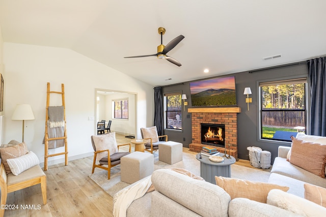 living room featuring a brick fireplace, light hardwood / wood-style flooring, ceiling fan, and vaulted ceiling