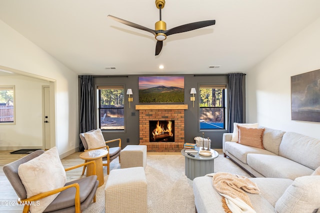 living room with vaulted ceiling, ceiling fan, light hardwood / wood-style flooring, and a fireplace