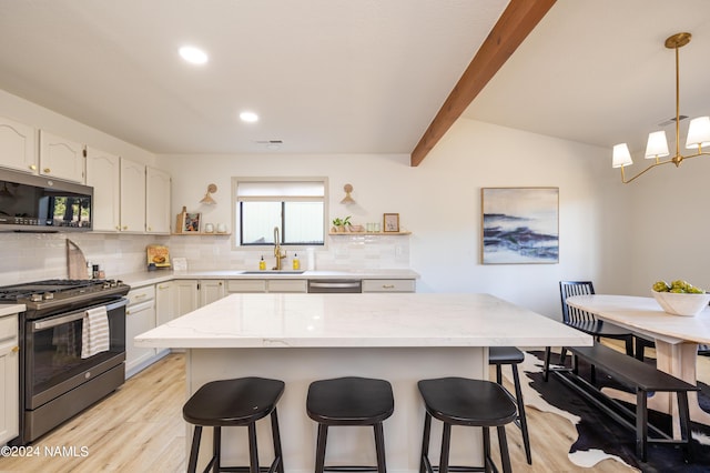 kitchen featuring sink, tasteful backsplash, a center island, and stainless steel appliances