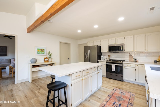 kitchen featuring backsplash, white cabinets, a center island, beamed ceiling, and stainless steel appliances