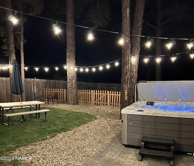 yard at twilight with a hot tub