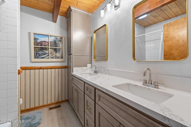 2468 N Strawberry Way, Flagstaff, AZ 86004 - bathroom featuring wood ceiling with exposed beams, wood finished floors, double vanity, a wainscoted wall, and a shower