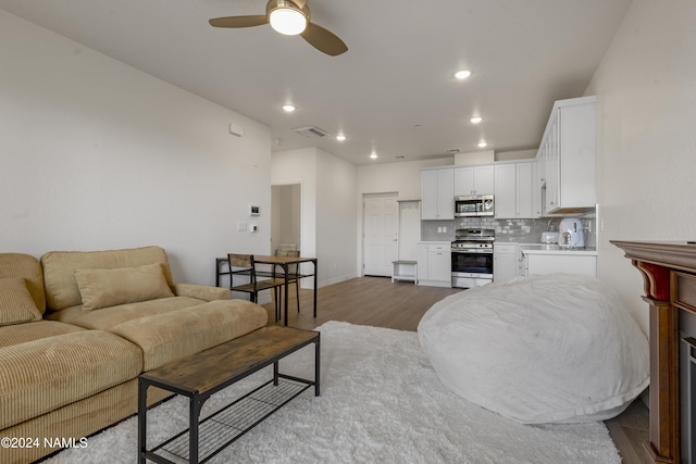 living room with ceiling fan and light hardwood / wood-style flooring