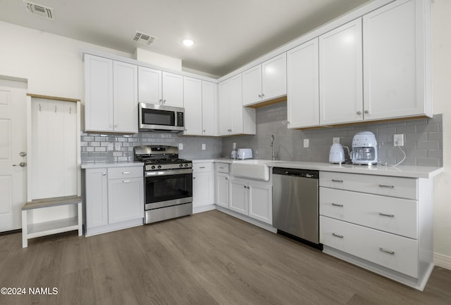 kitchen featuring wood-type flooring, white cabinets, sink, backsplash, and stainless steel appliances