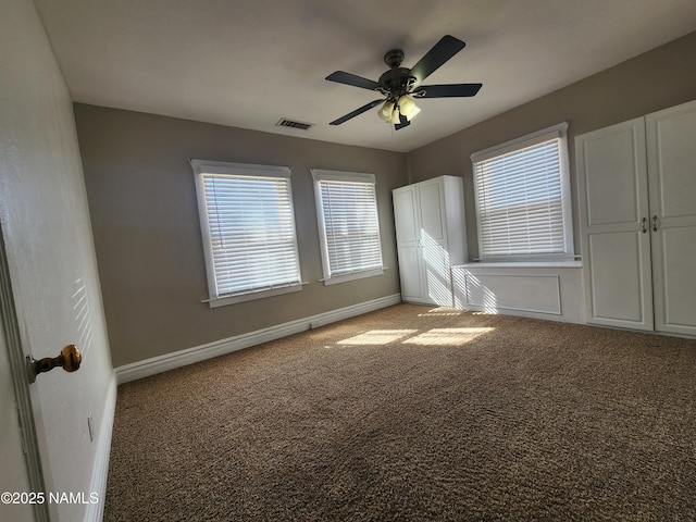 carpeted spare room featuring a ceiling fan, visible vents, and baseboards