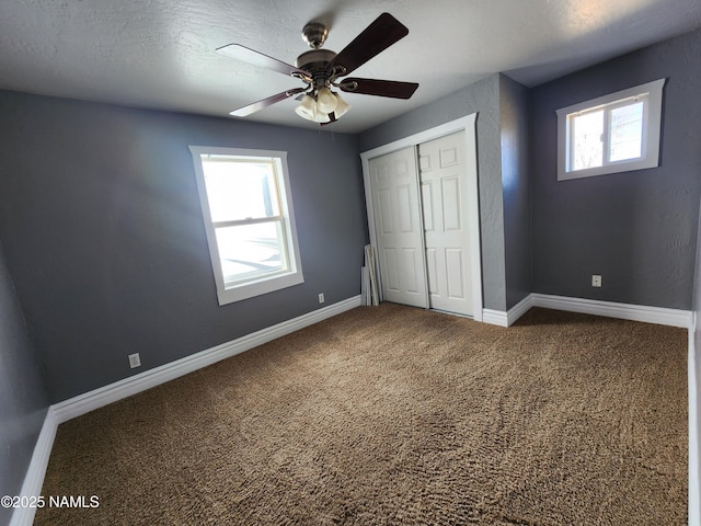 unfurnished bedroom featuring carpet floors, a closet, ceiling fan, and baseboards