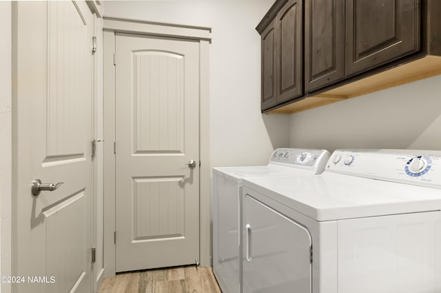 laundry area featuring light wood-style flooring, cabinet space, and washing machine and dryer