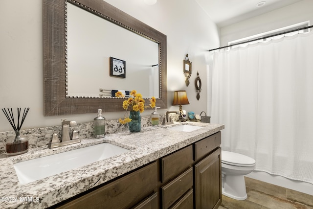 bathroom with toilet, double vanity, and a sink