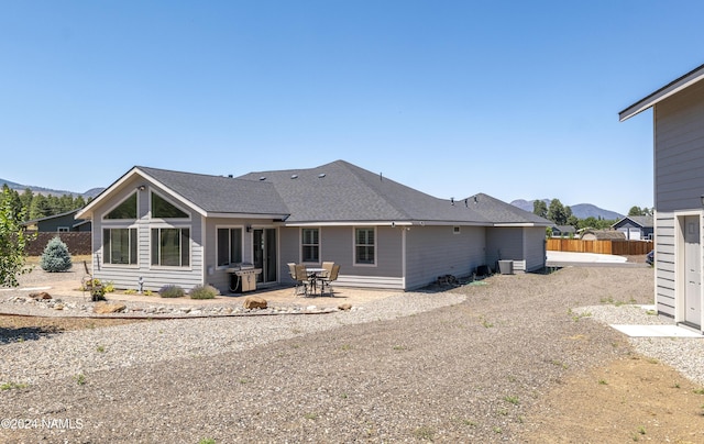 rear view of property with a patio, a mountain view, and fence