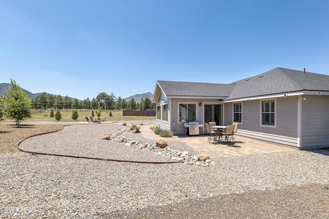 exterior space with a patio area, a mountain view, and a shingled roof