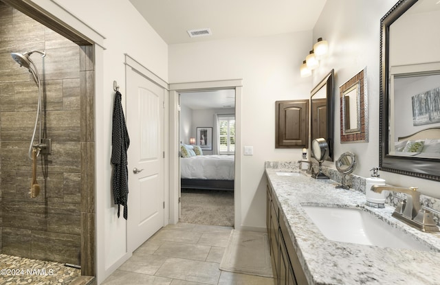 bathroom with visible vents, tiled shower, connected bathroom, and a sink