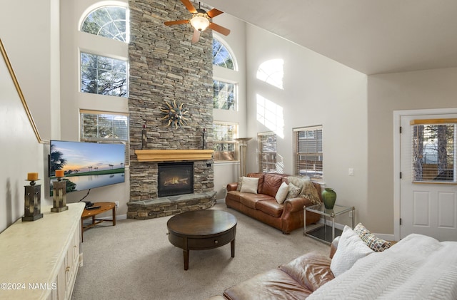 carpeted living room featuring a towering ceiling, a wealth of natural light, ceiling fan, and a fireplace