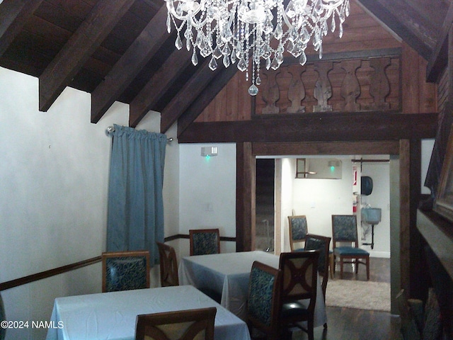 dining space with wood-type flooring, a chandelier, and vaulted ceiling with beams