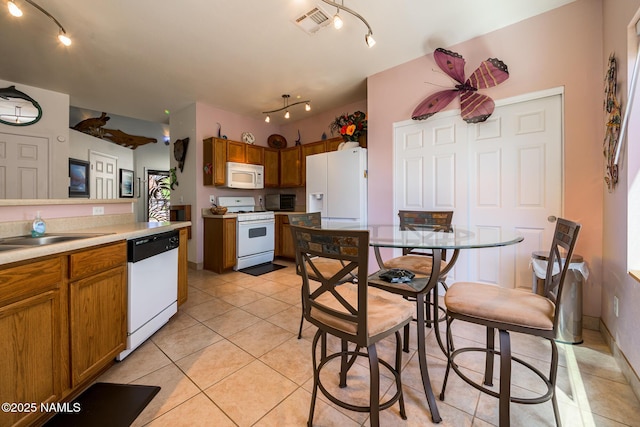 9129 W Arden Ln, Bellemont, AZ 86015 - kitchen featuring white appliances, rail lighting, brown cabinetry, and light tile patterned floors