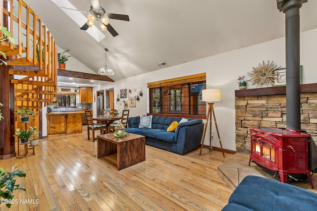 435 N Laramy Ln, Parks, AZ 86018 - living room featuring a wood stove, ceiling fan, light wood-style flooring, high vaulted ceiling, and stairway