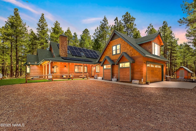 435 N Laramy Ln, Parks, AZ 86018 - rustic home featuring covered porch, roof mounted solar panels, driveway, an attached garage, and a chimney