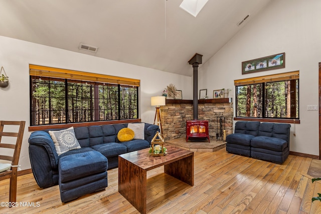 435 N Laramy Ln, Parks, AZ 86018 - living room featuring a wood stove, light wood-style flooring, a skylight, healthy amount of natural light, and high vaulted ceiling
