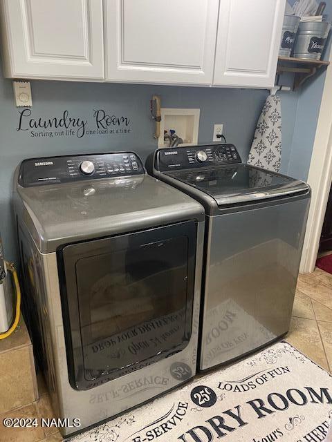 washroom with light tile patterned floors, washer and clothes dryer, and cabinets