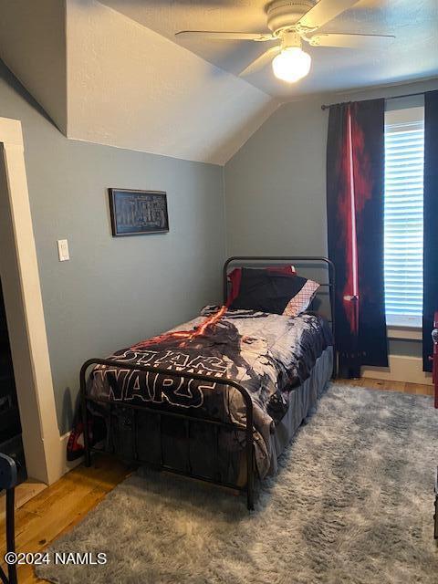 bedroom with hardwood / wood-style flooring, vaulted ceiling, and ceiling fan