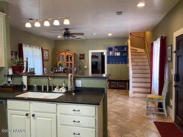 kitchen featuring dishwasher, sink, white cabinets, light tile patterned floors, and ceiling fan