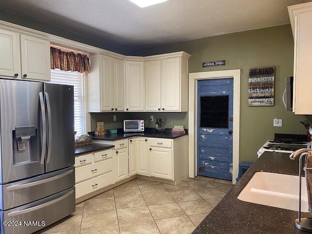 kitchen featuring white cabinetry, stainless steel appliances, light tile patterned flooring, and sink