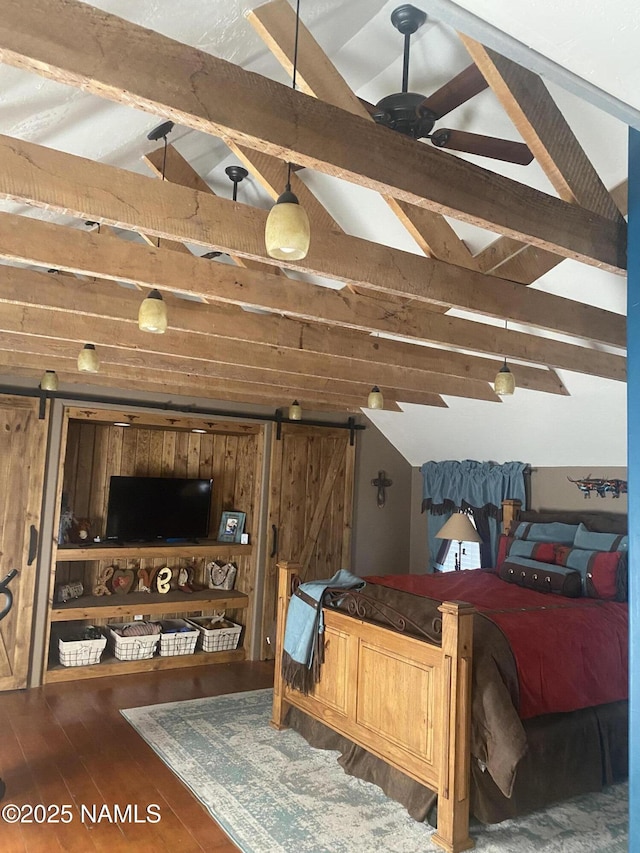 bedroom with wooden walls, a barn door, hardwood / wood-style floors, and vaulted ceiling with beams