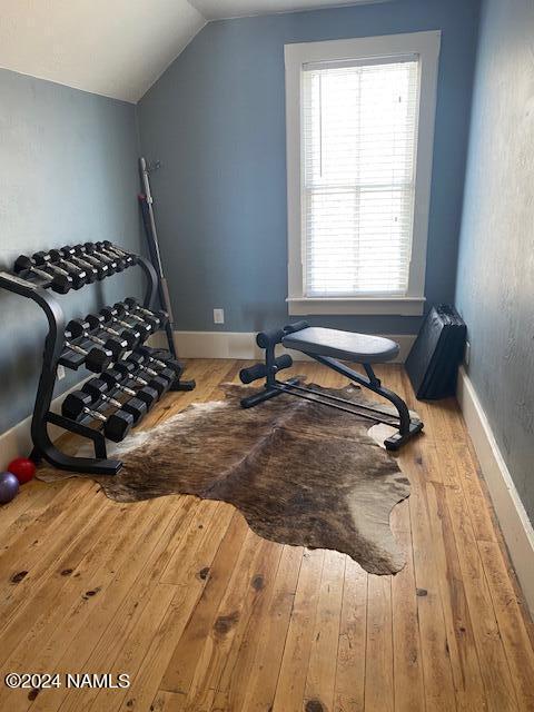 exercise room with lofted ceiling and wood-type flooring