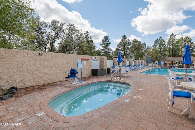 view of pool with a hot tub and a patio