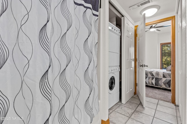 laundry area featuring ceiling fan and stacked washer / dryer