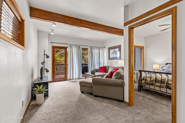 carpeted living area featuring beam ceiling, a ceiling fan, and baseboards
