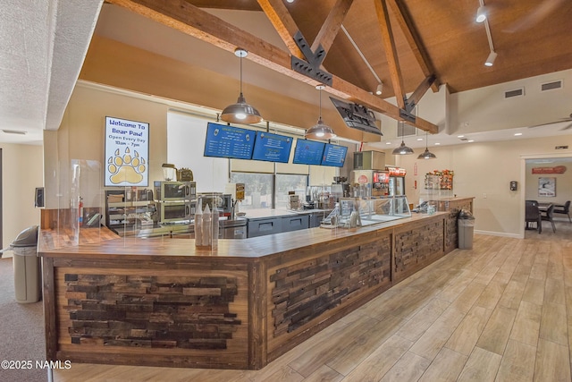 kitchen with rail lighting, high vaulted ceiling, decorative light fixtures, beamed ceiling, and light wood-type flooring