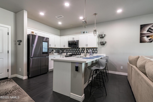 kitchen featuring white cabinetry, a breakfast bar area, pendant lighting, and stainless steel fridge