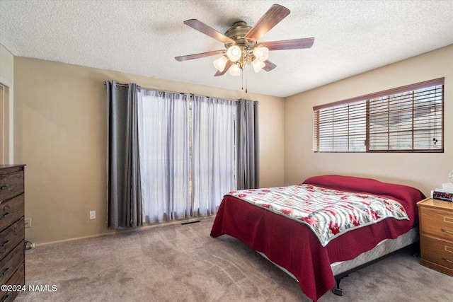 carpeted bedroom featuring ceiling fan and a textured ceiling